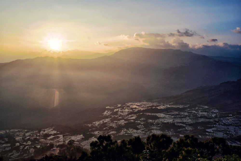 the sun is setting over a mountain range