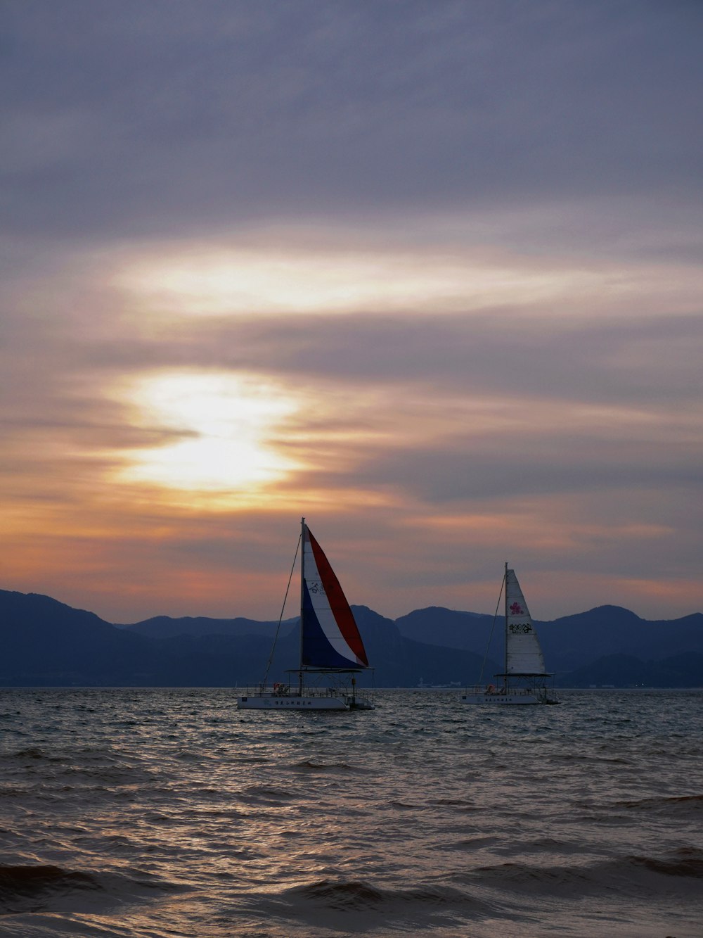 a couple of sail boats floating on top of a body of water