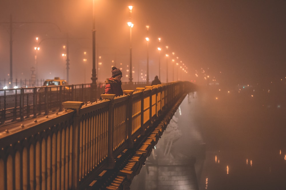 uma pessoa em pé em uma ponte à noite