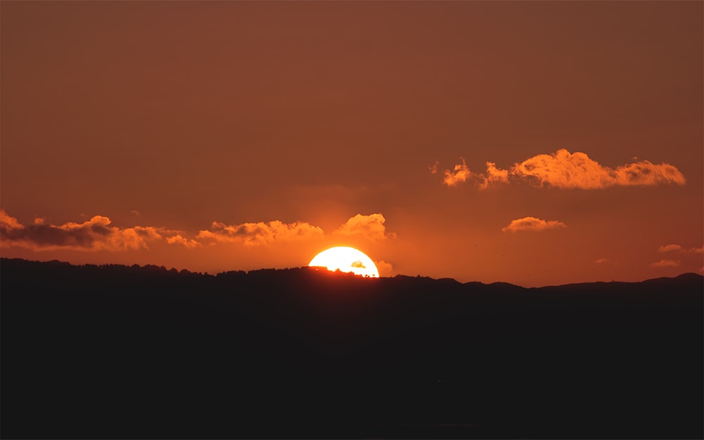 the sun is setting over a mountain range