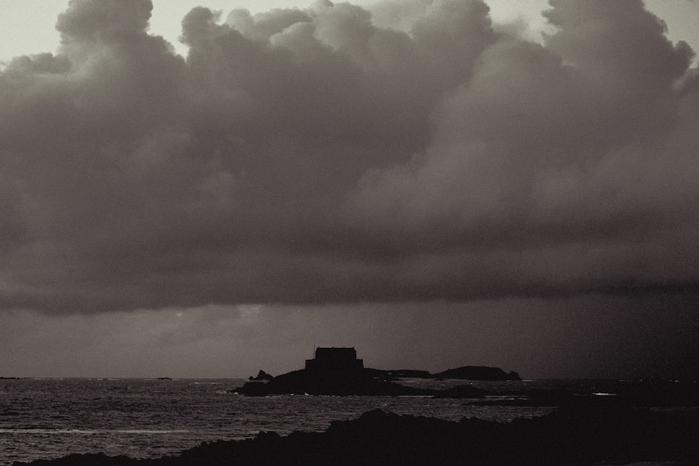 a black and white photo of a lighthouse under a cloudy sky