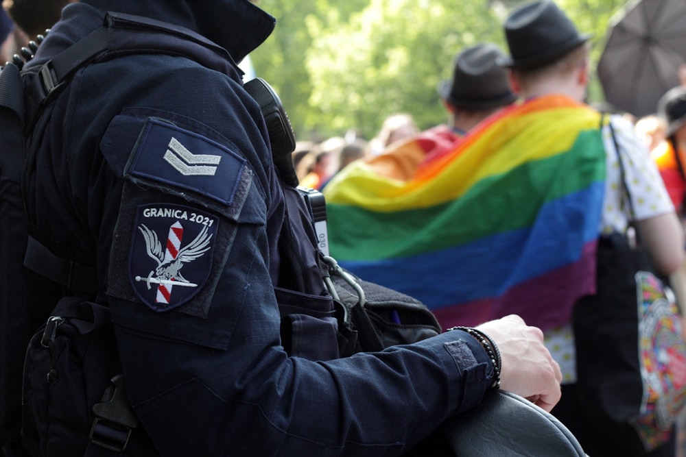 um homem com um uniforme da polícia segurando uma bandeira do arco-íris
