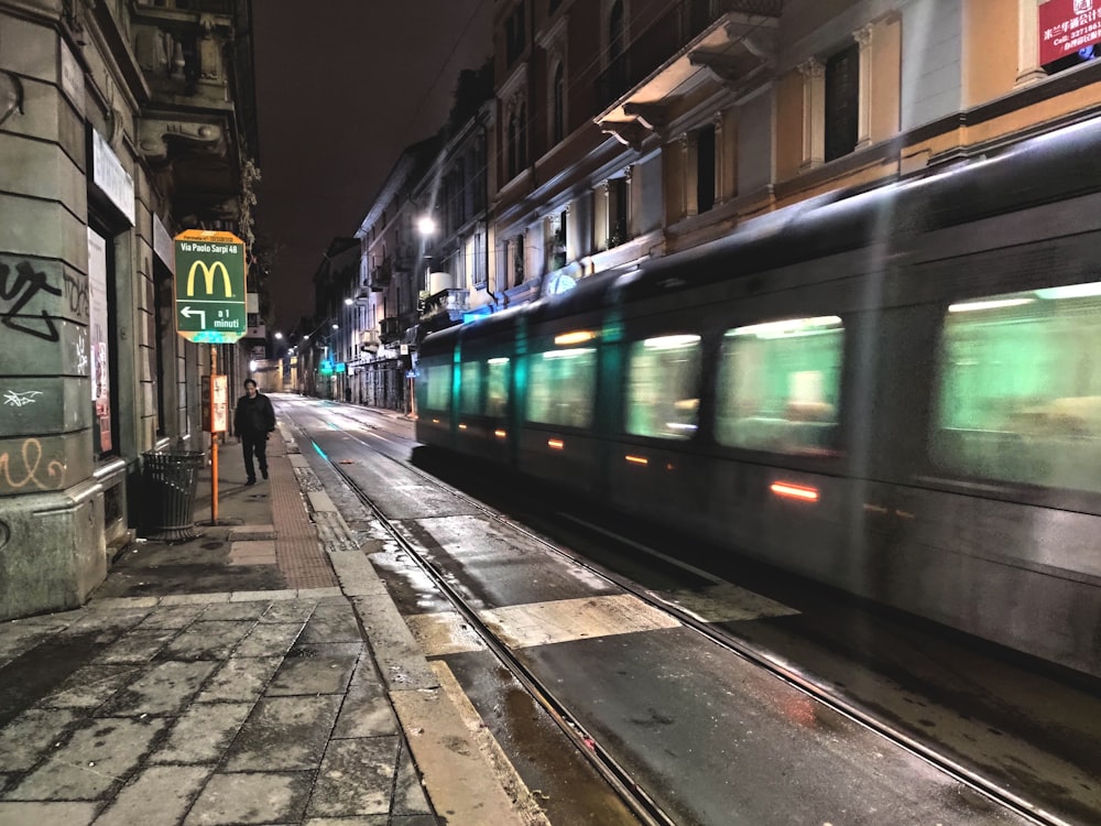 a man walking down a sidewalk next to a train