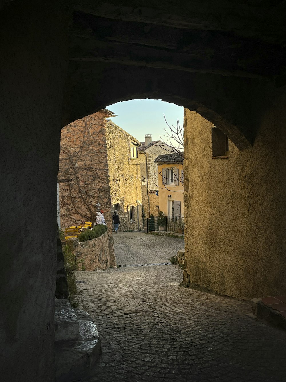 a cobblestone street with a person walking down it
