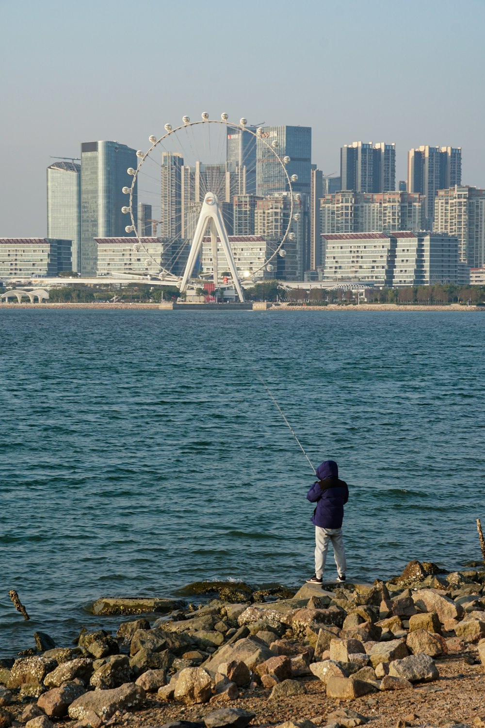 a man standing on a rocky shore next to a body of water