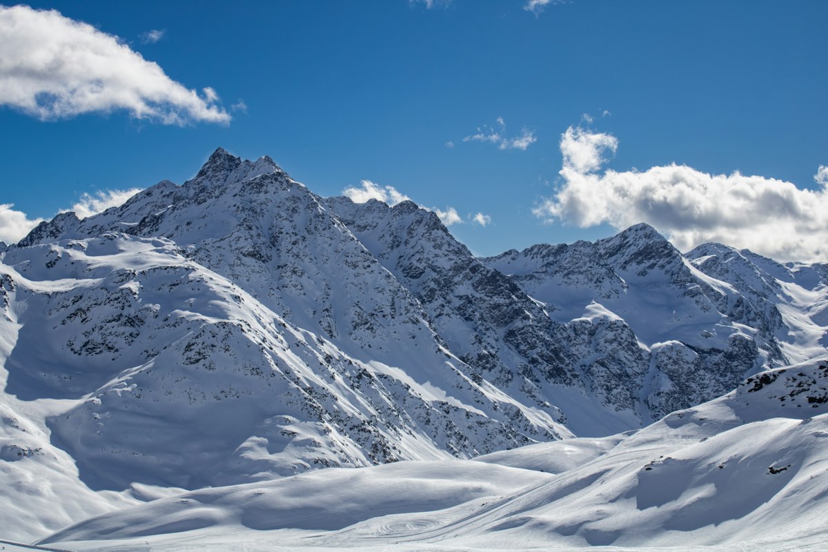 Catena montuosa innevata sotto un cielo azzurro nuvoloso nelle Alpi italiane