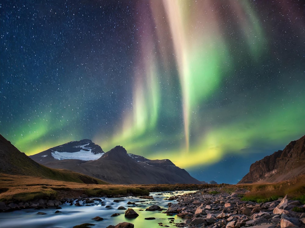 a stream running through a lush green valley under a sky filled with stars