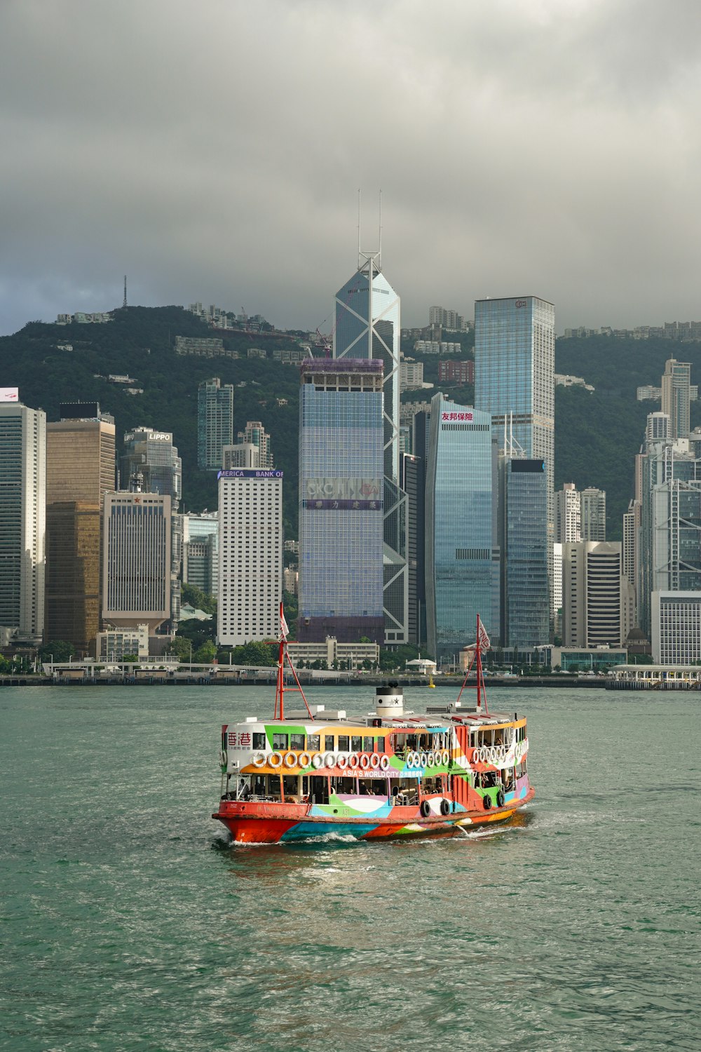 a colorful boat in a body of water with a city in the background