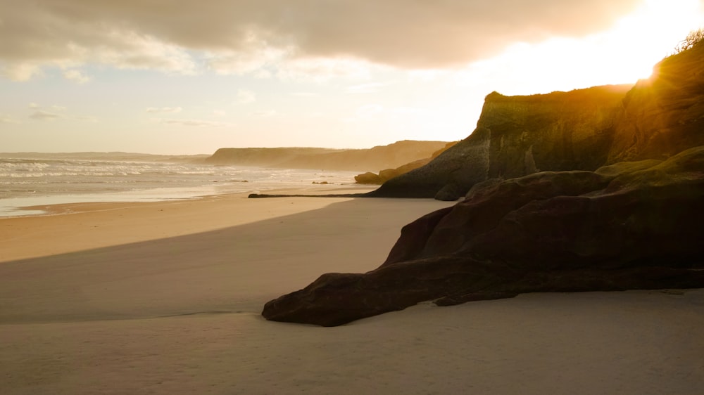 the sun is setting on the beach near the water