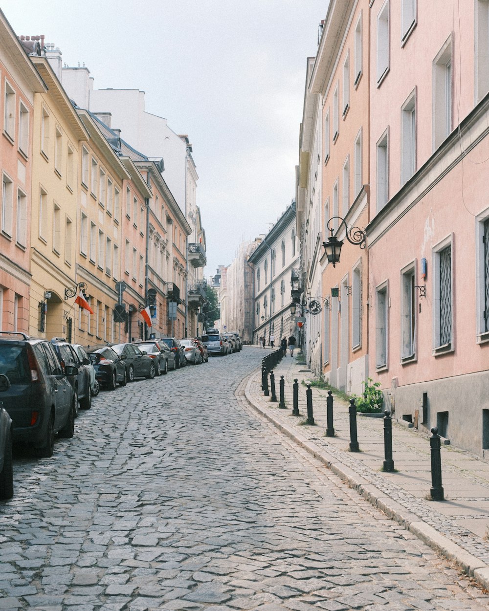 a cobblestone street lined with parked cars