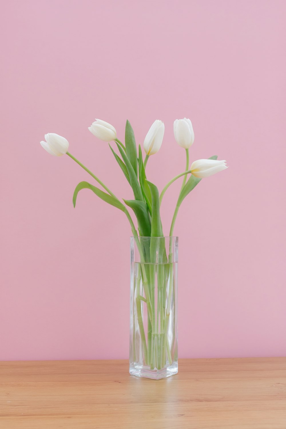 a glass vase filled with white flowers on top of a wooden table