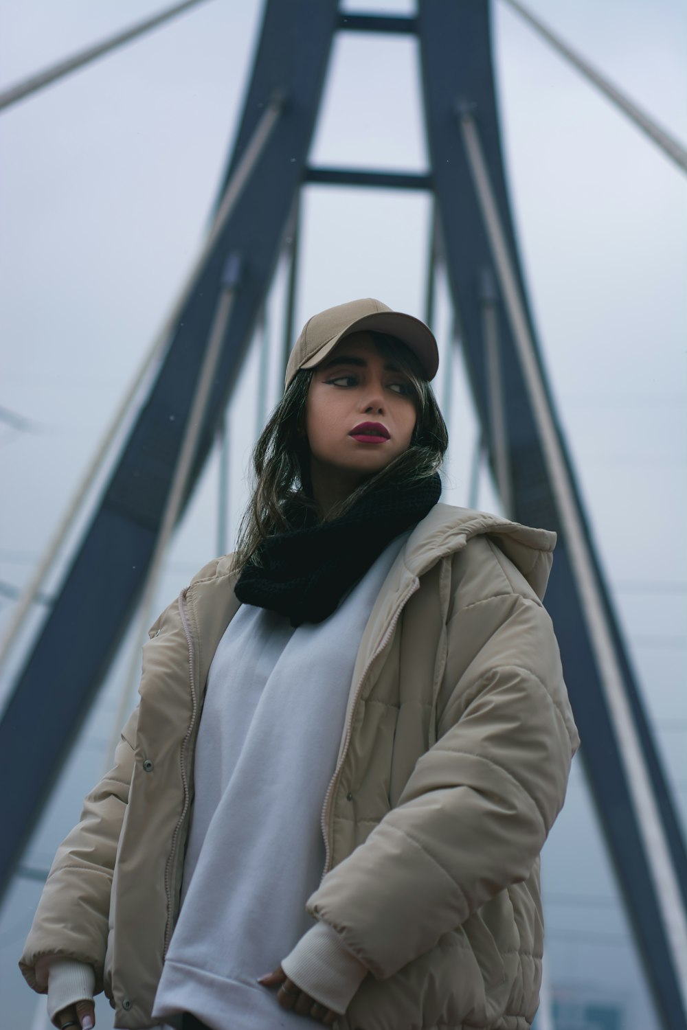 a woman standing on a bridge wearing a hat and coat