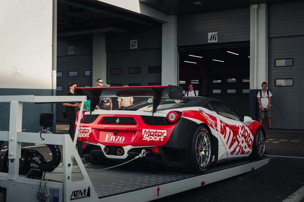 a red and white sports car being towed by a tow truck