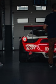 a man standing next to a red and white race car
