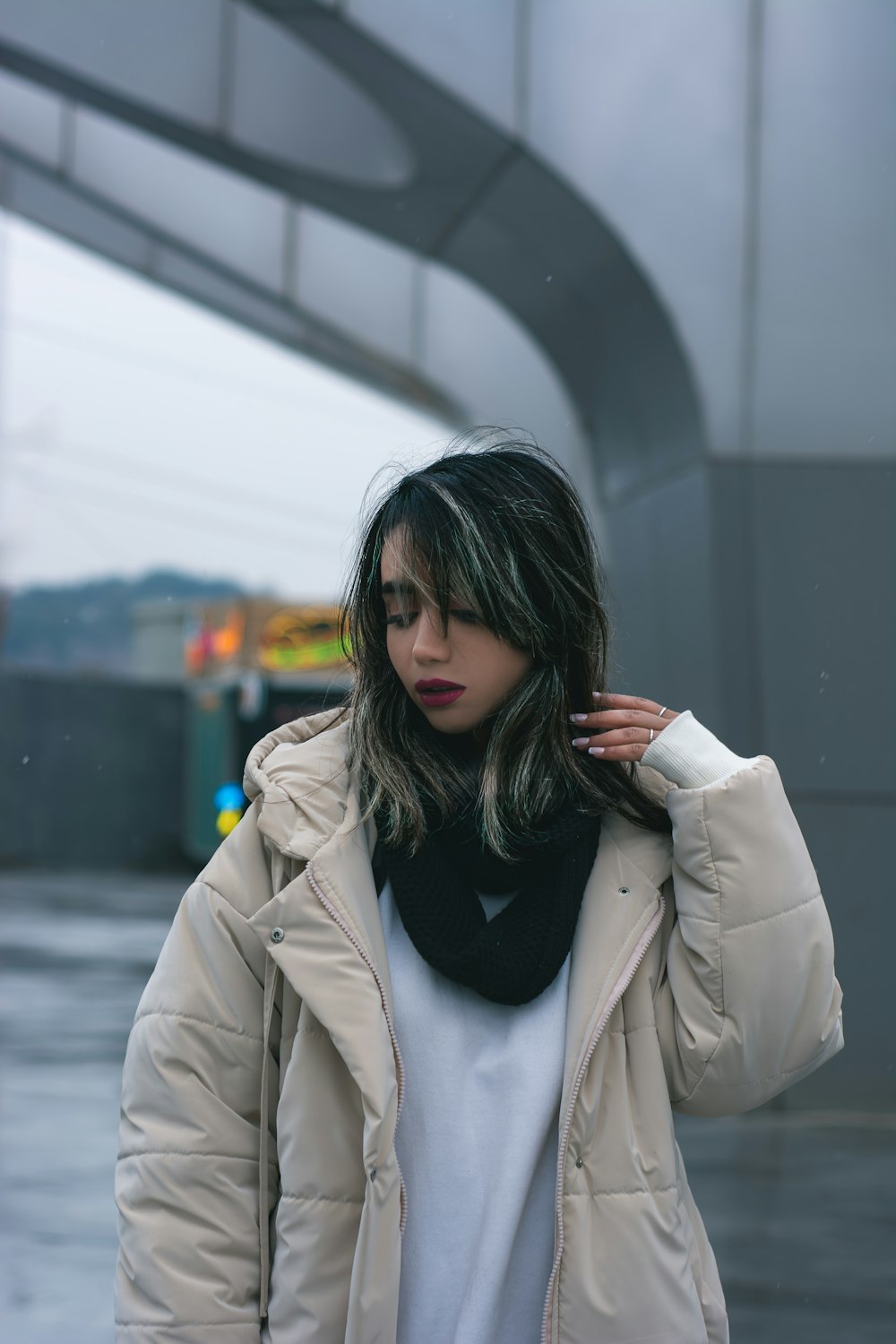 a woman standing in the rain wearing a jacket and scarf