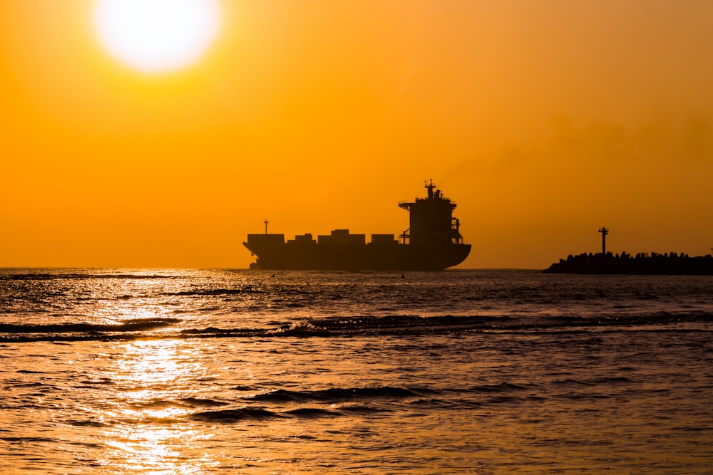 a large cargo ship in the ocean at sunset