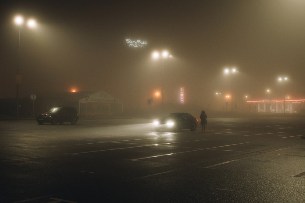 a couple of cars driving down a foggy street