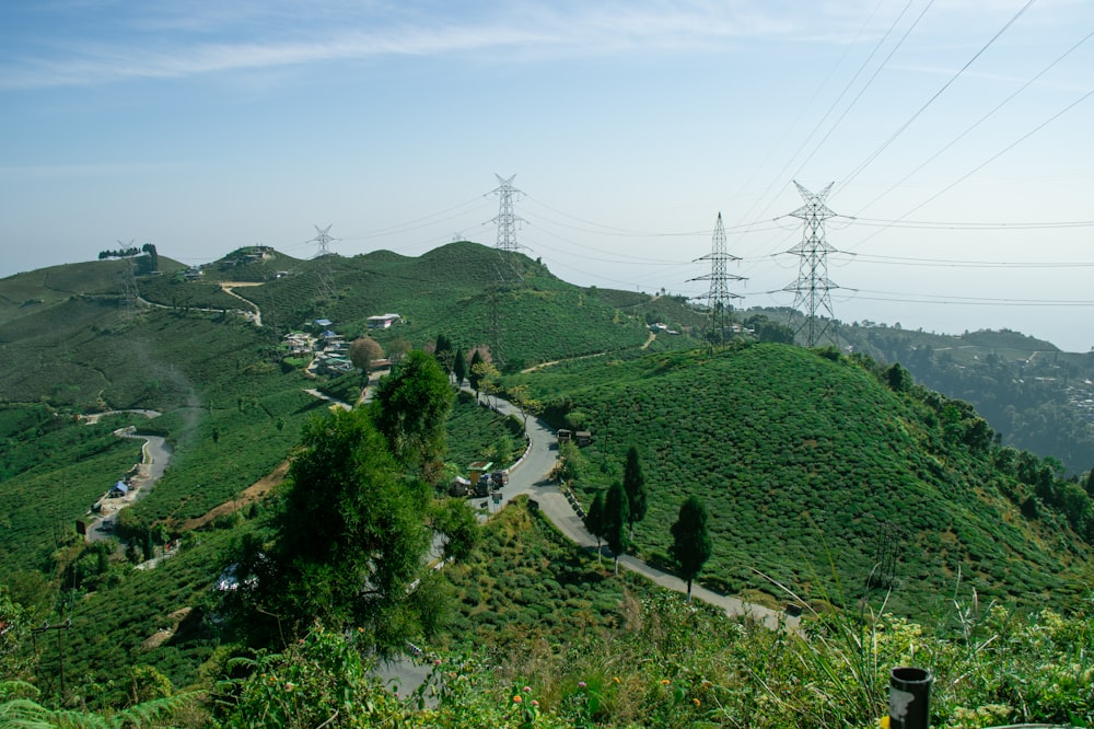 a winding road on a hill with power lines in the background