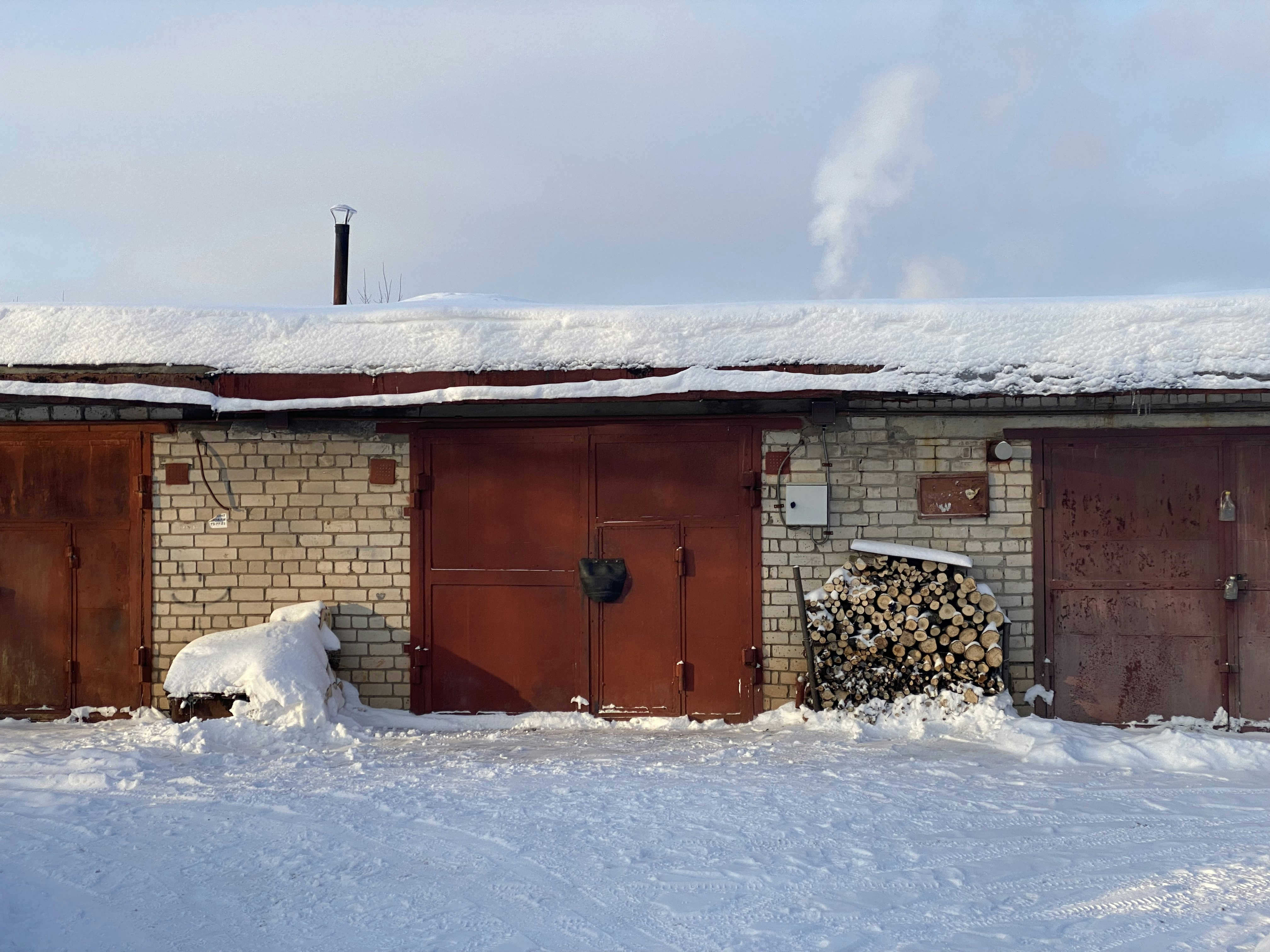 a brick building with a pile of wood in front of it