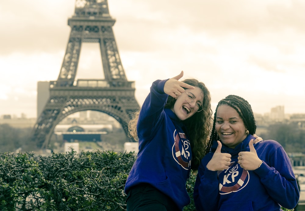 two girls posing for a picture in front of the eiffel tower