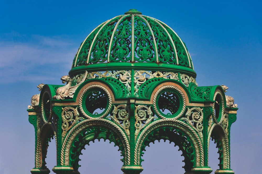 a green clock tower with a blue sky in the background