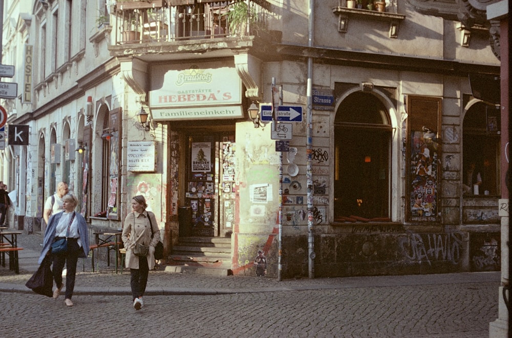 a couple of people walking down a street next to a tall building