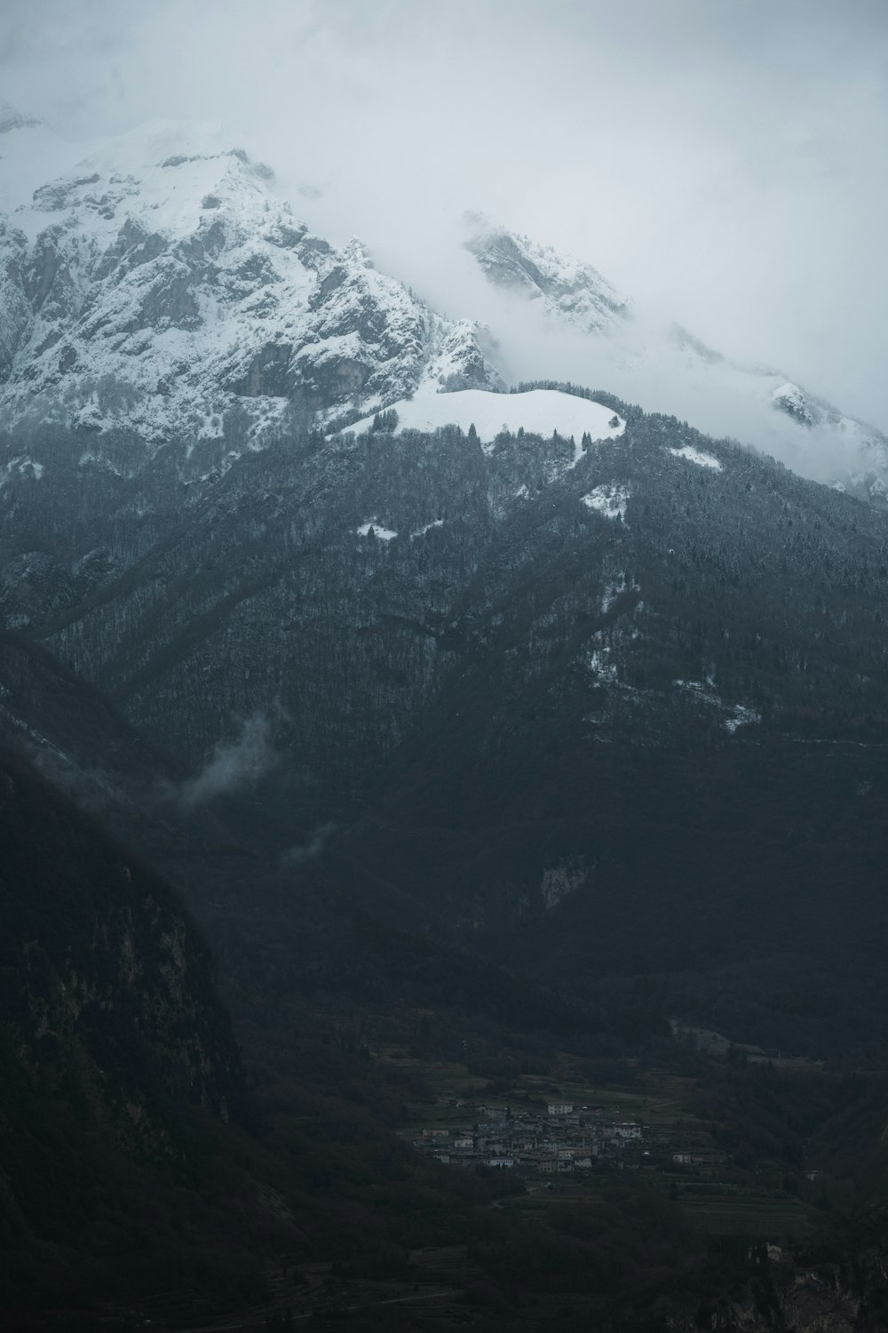 a mountain covered in snow and clouds in the distance