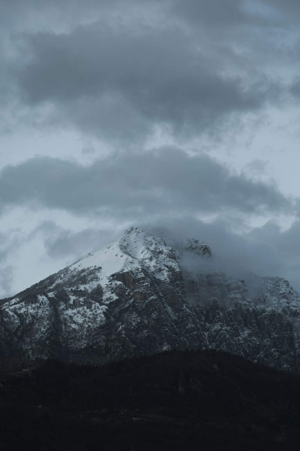 a mountain covered in snow under a cloudy sky