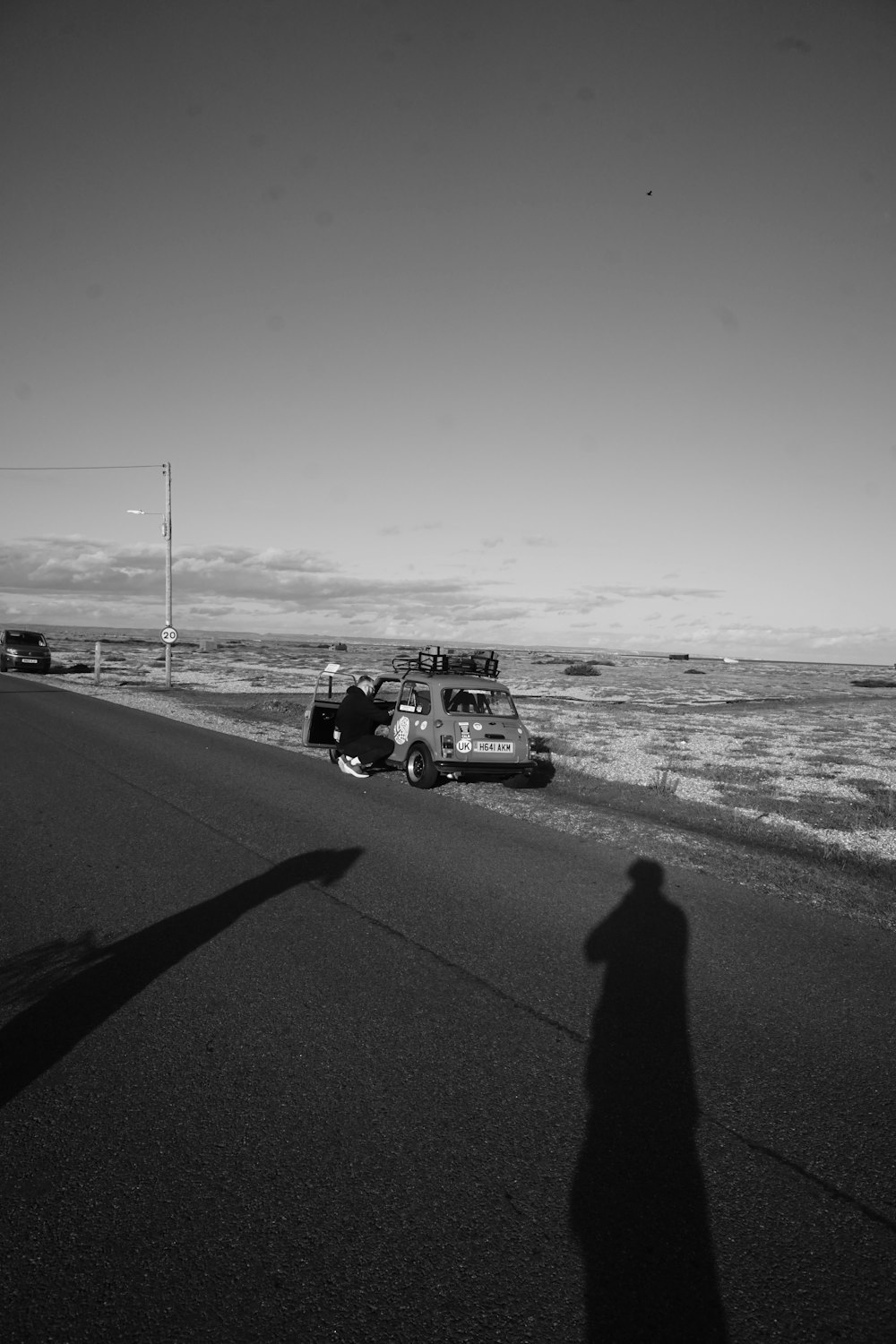 a person standing on the side of a road next to the ocean