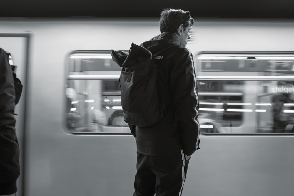 a man with a backpack standing in front of a train
