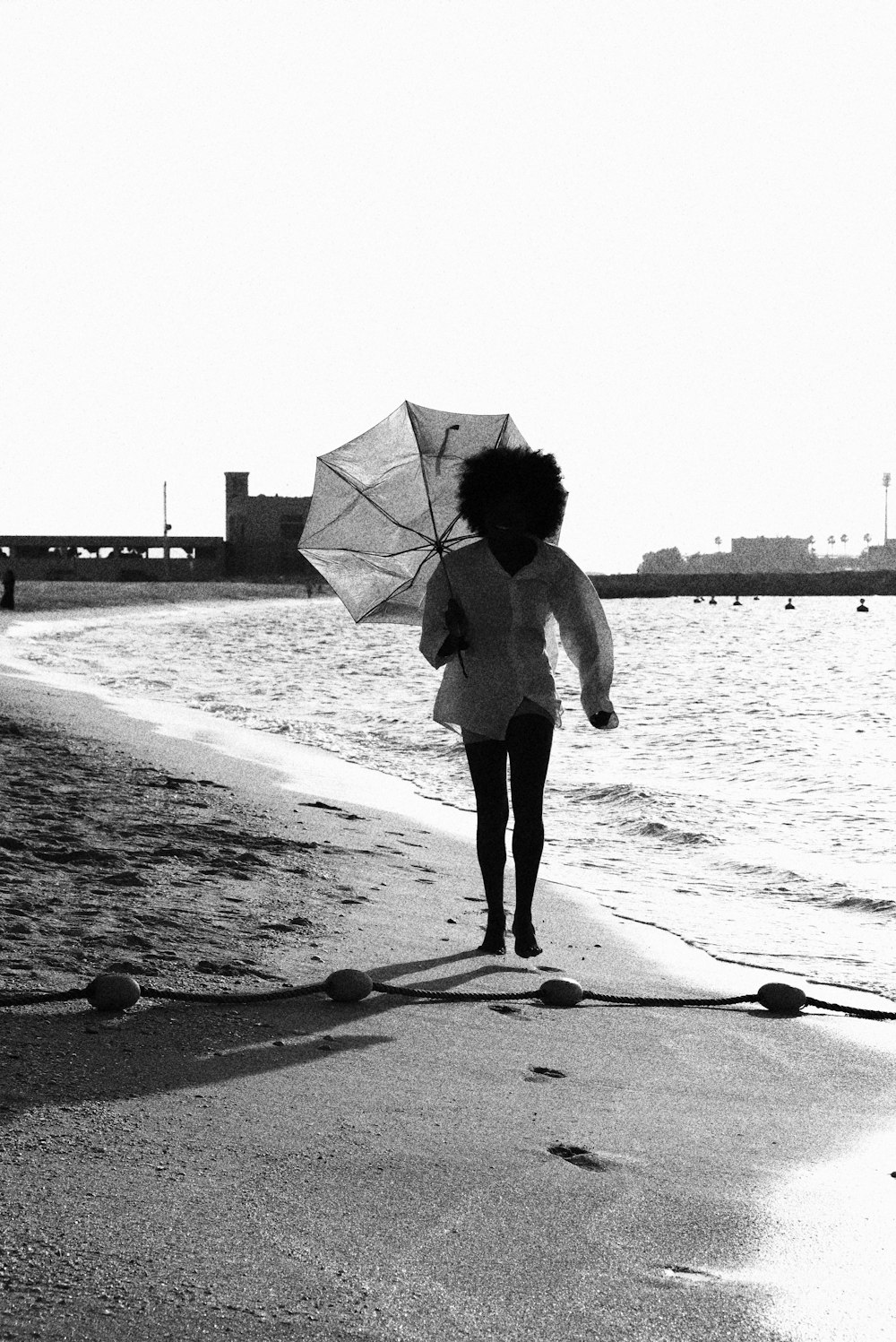a woman walking on the beach with an umbrella