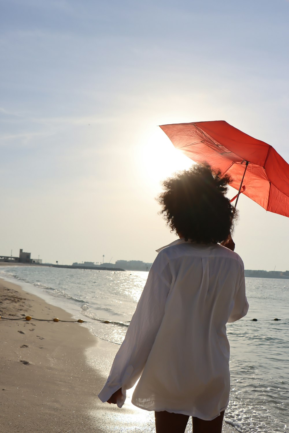 una donna che cammina su una spiaggia con in mano un ombrello