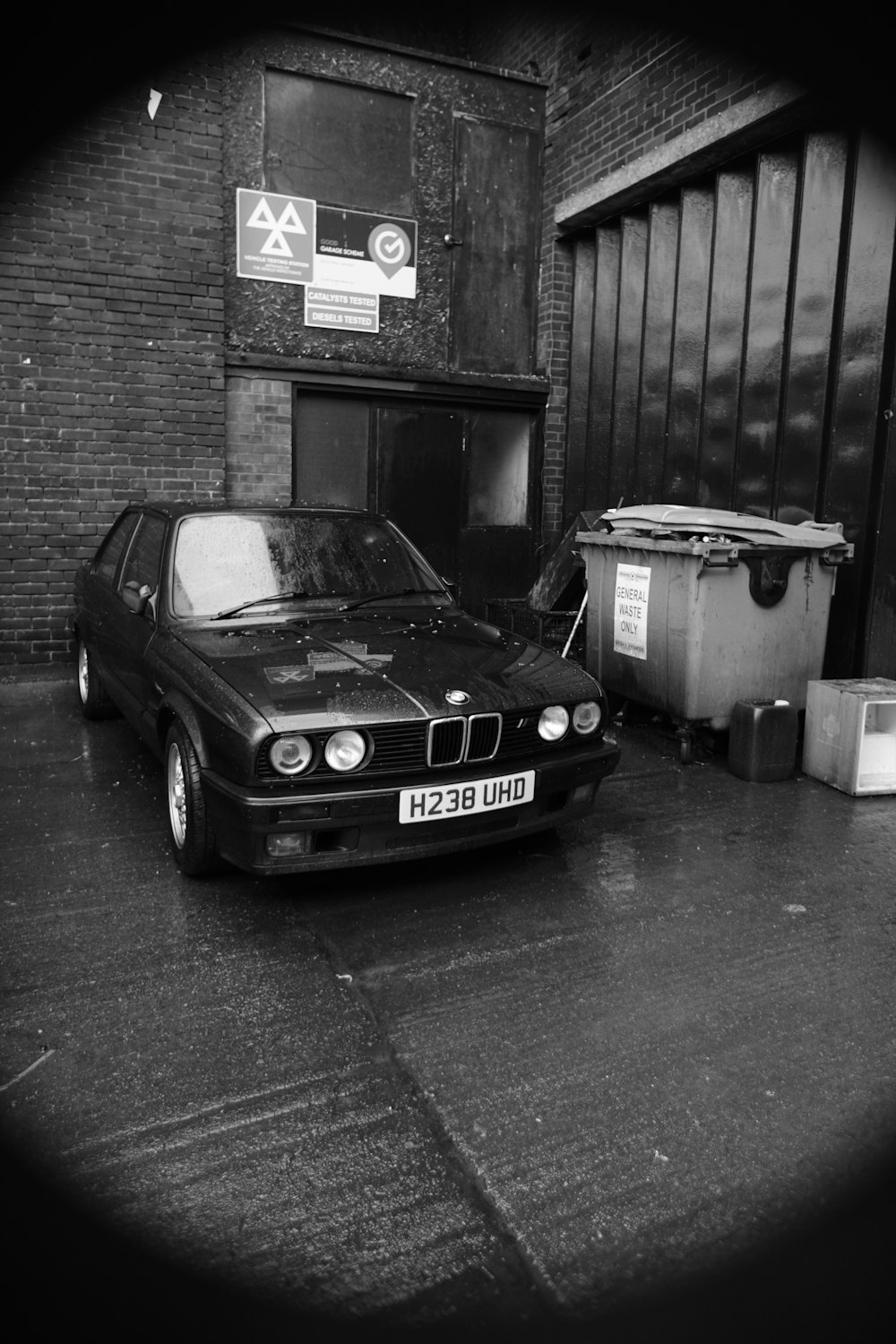 a black and white photo of a car parked in front of a building