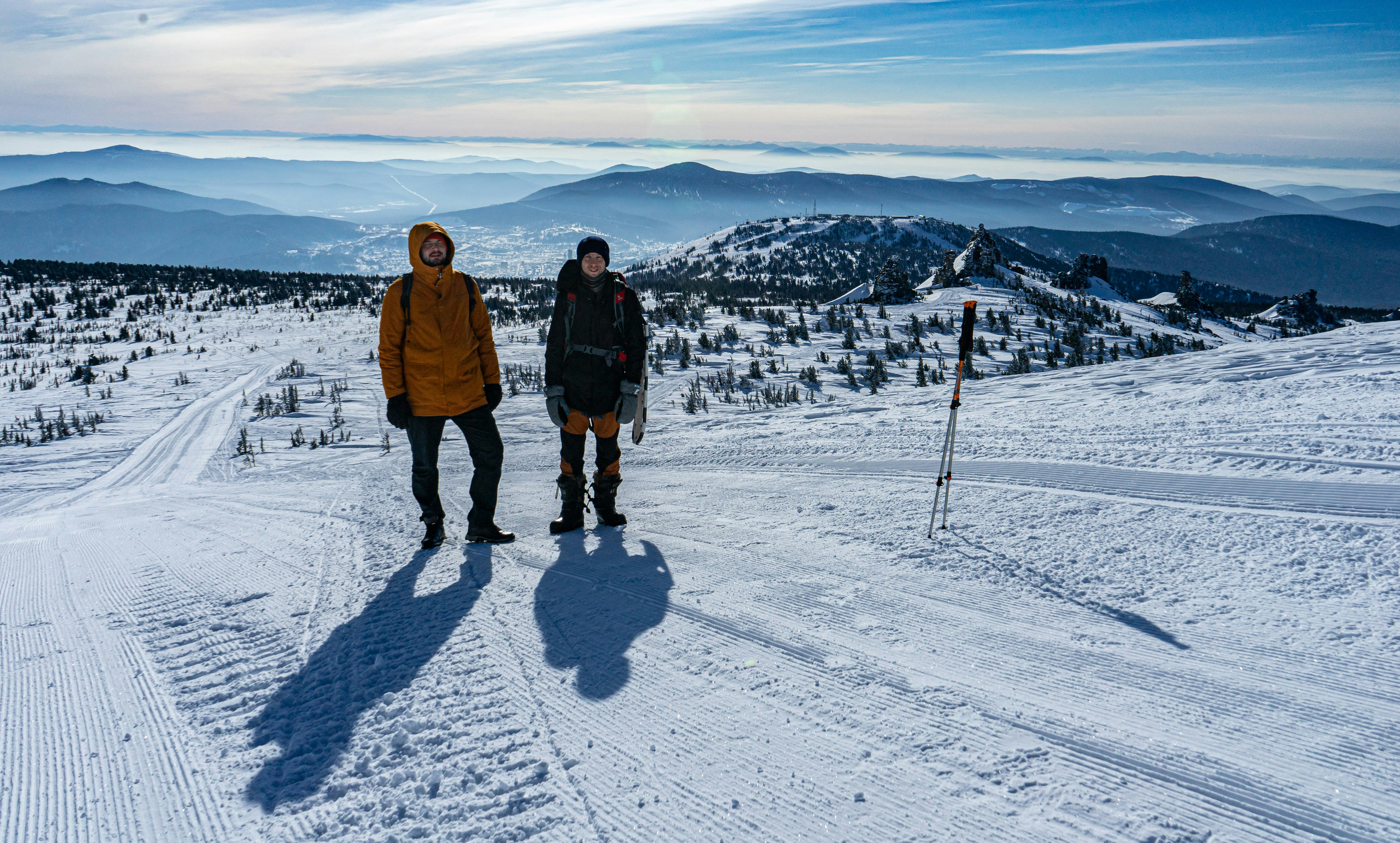 пара человек стоит на вершине заснеженного склона
