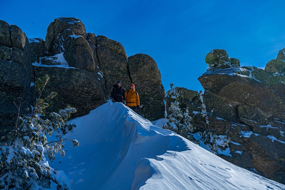 a couple of people standing on top of a snow covered slope