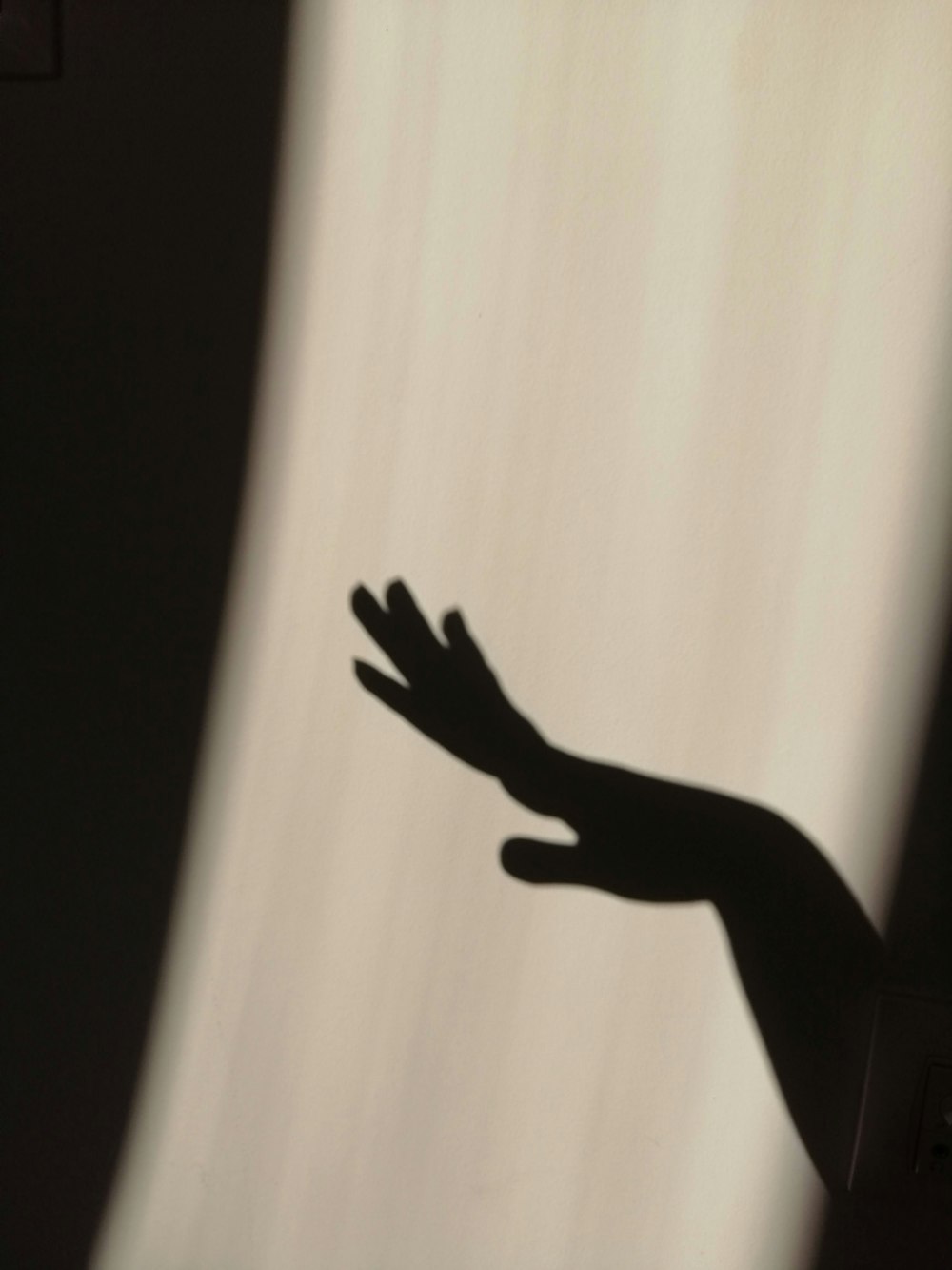 a shadow of a person's hand on a wall