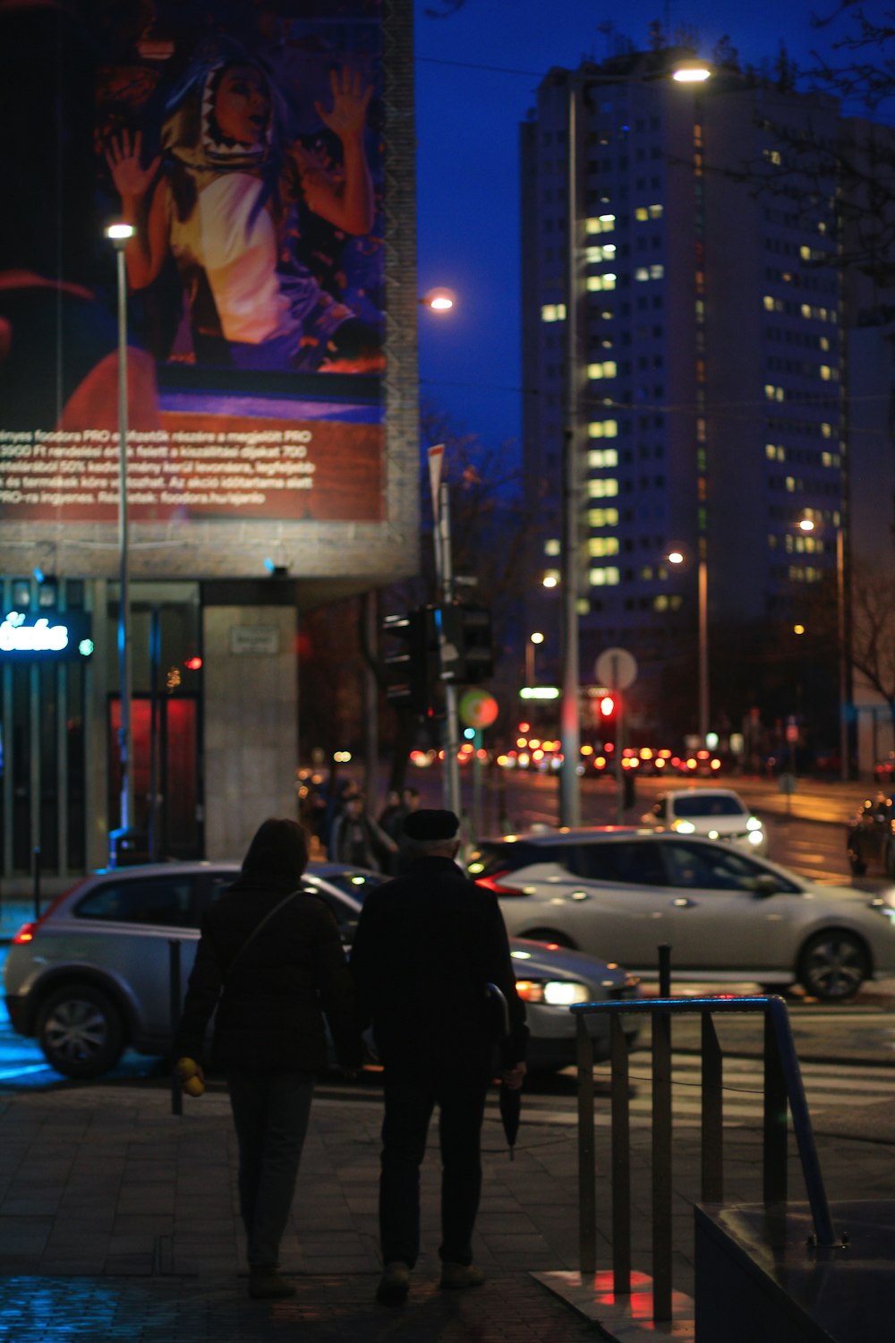 a couple of people walking down a street at night