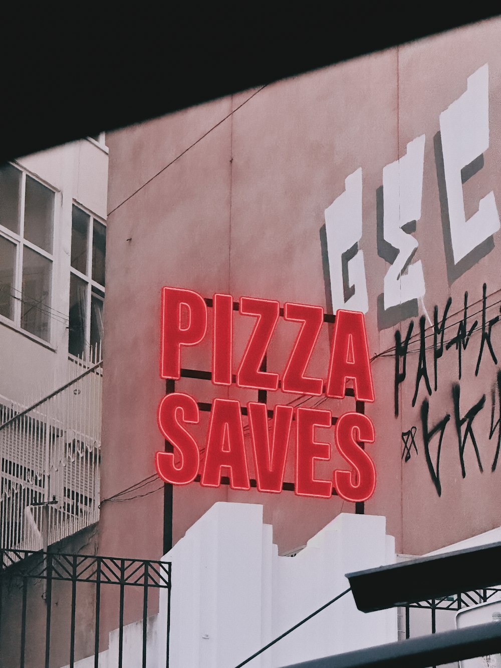 a neon sign that says pizza savies on a building
