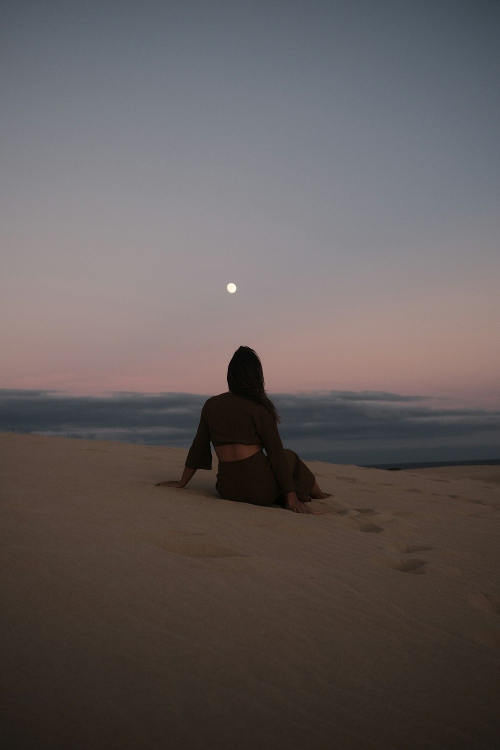 uma mulher sentada em cima de uma praia de areia