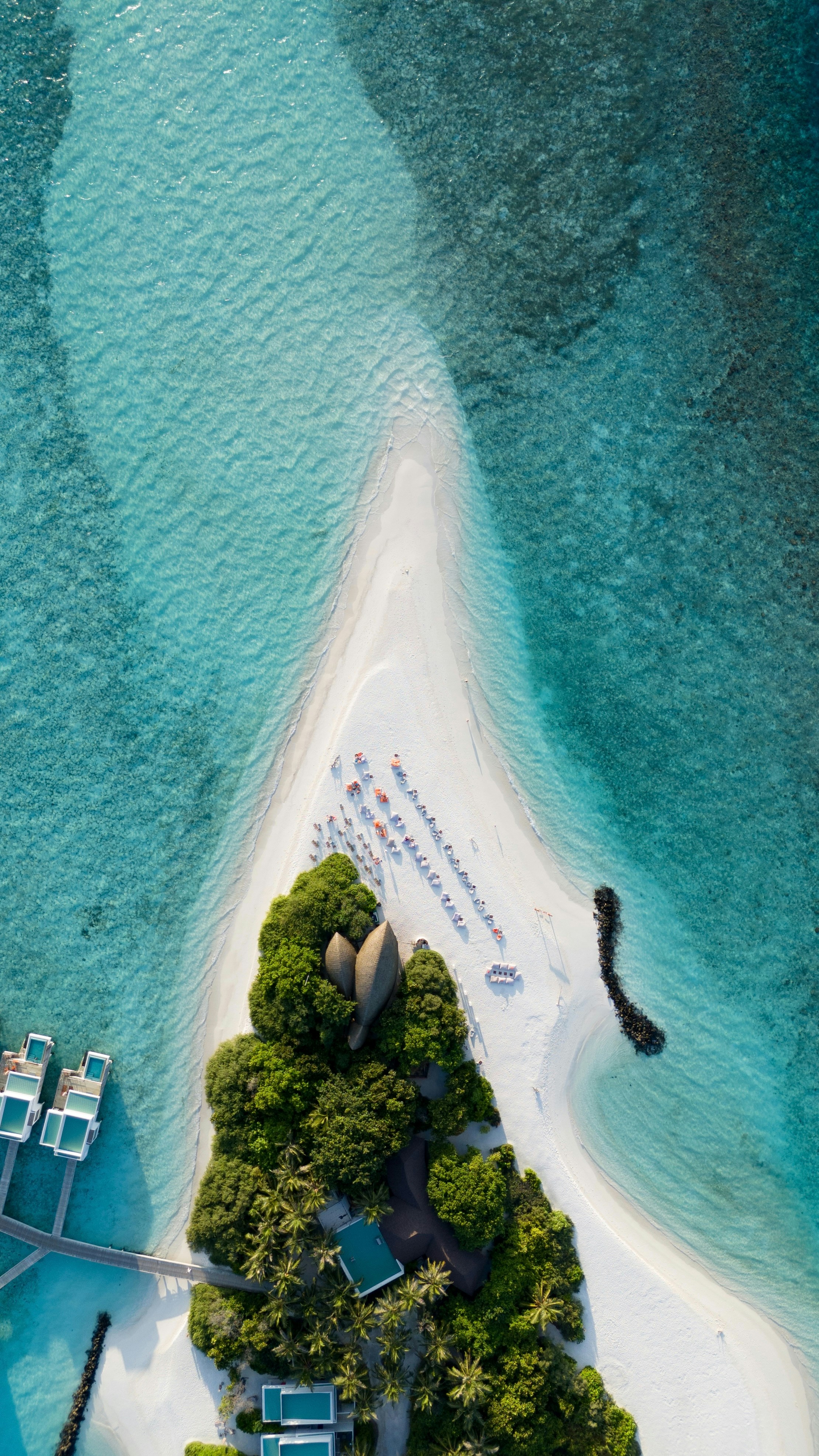 Aerial view of a white sandbank surrounded by turquoise water with resort villas