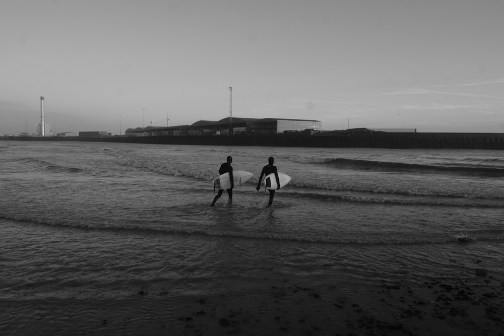two surfers walking into the ocean with their surfboards