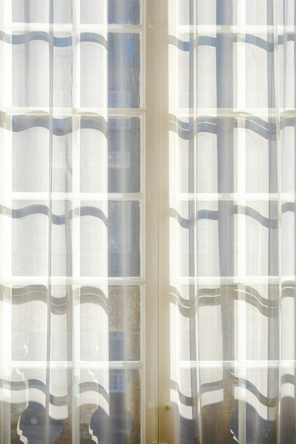 a cat sitting on a window sill in front of a curtain