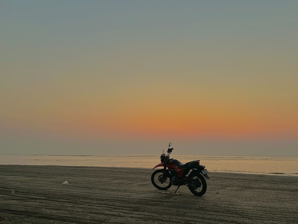 une moto garée sur la plage au coucher du soleil