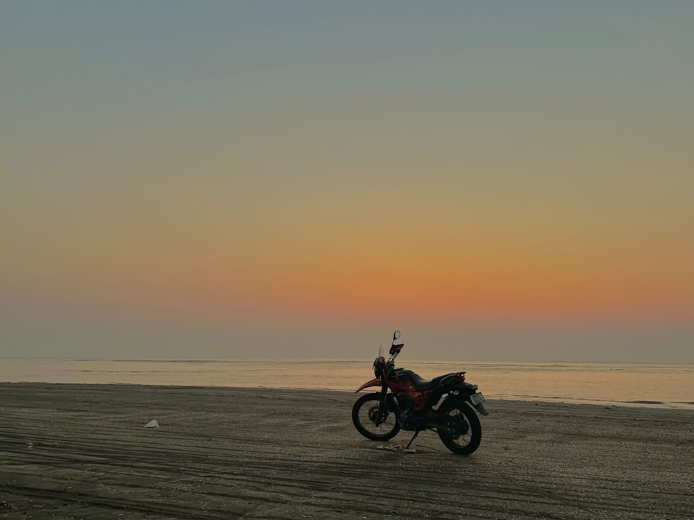 ein Motorrad, das bei Sonnenuntergang am Strand geparkt ist