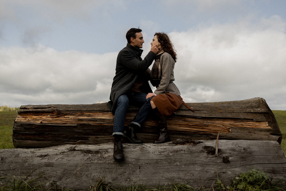 a man and a woman sitting on a log