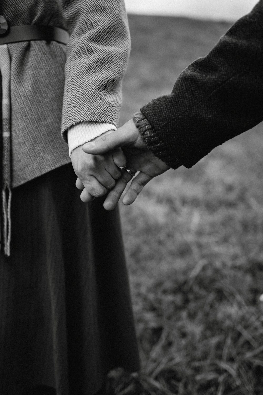 a black and white photo of two people holding hands