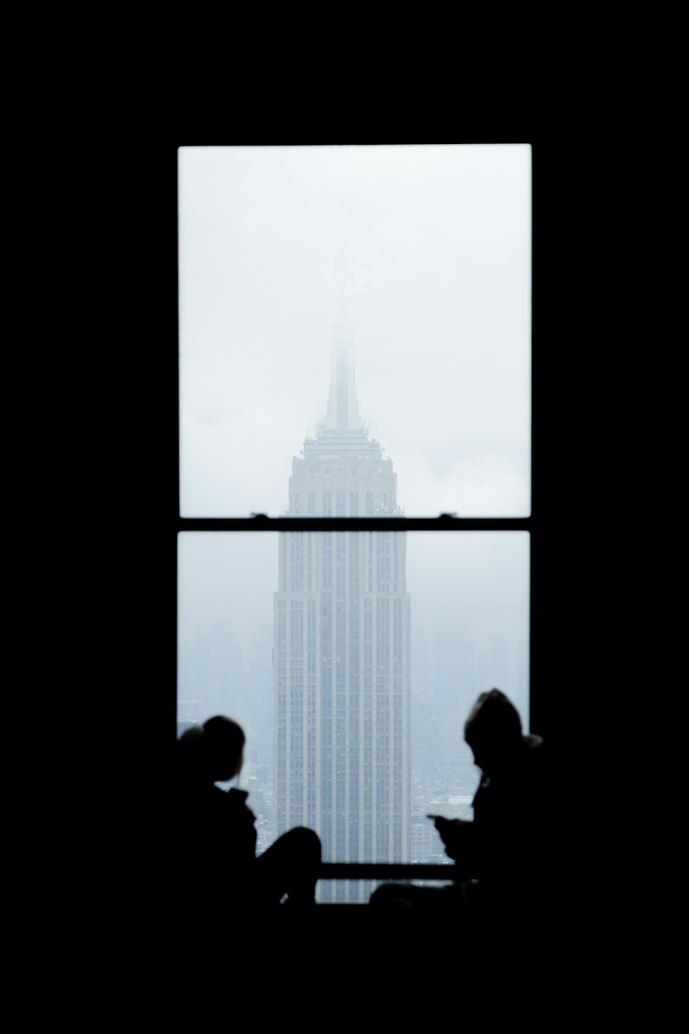 a couple of people sitting in front of a window