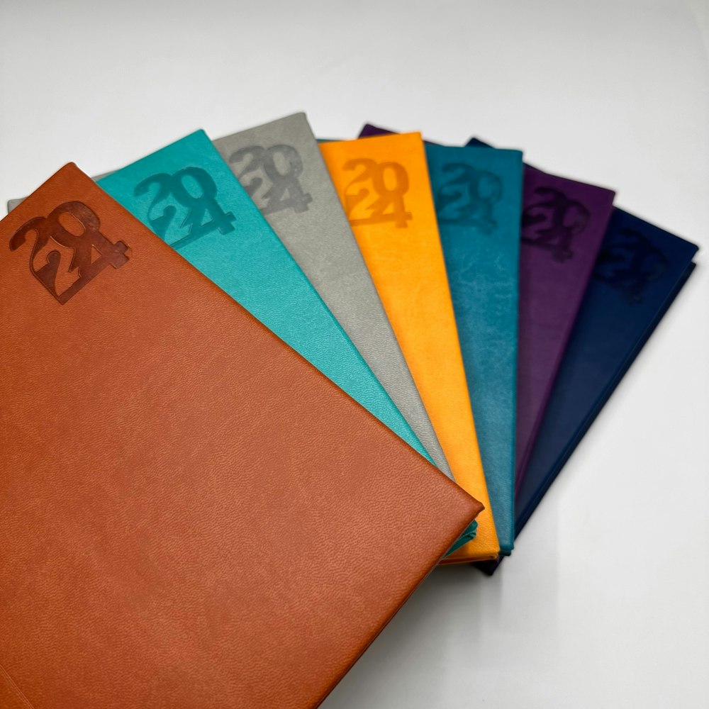 a stack of colored papers with a monogrammed logo