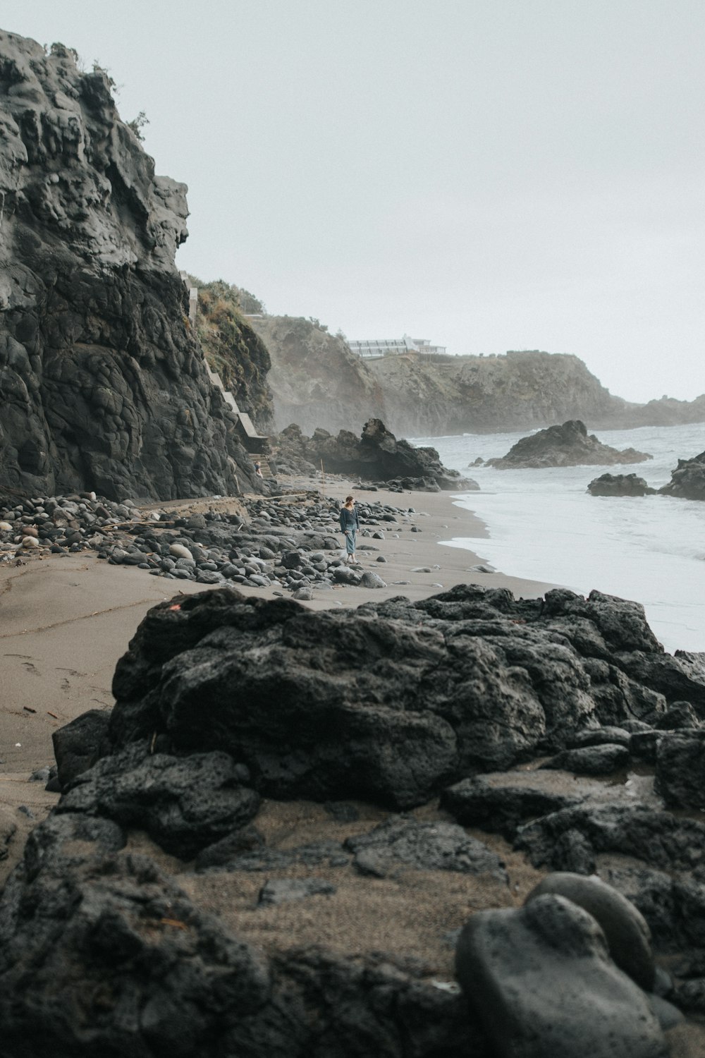 una persona parada en una playa rocosa junto al océano