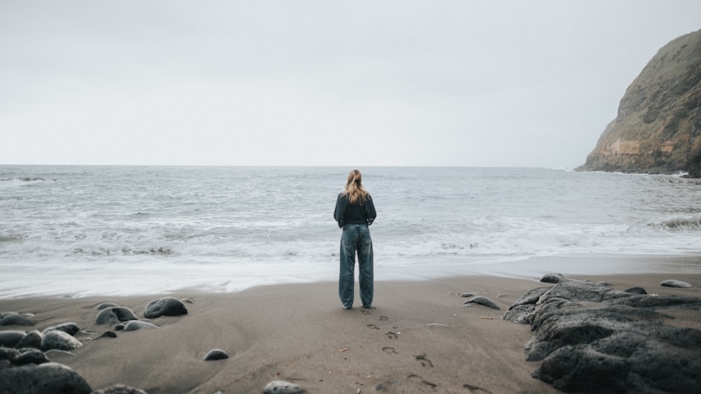 uma mulher em pé em uma praia ao lado do oceano